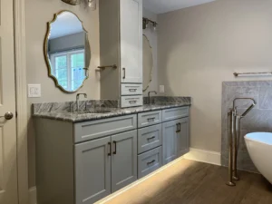Double vanity with illuminated toe-kick and gold-framed mirrors