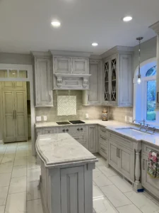 Bright and refreshed kitchen space with a stylish backsplash, gray cabinets, and polished marble countertops.