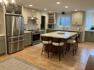 Modern open-concept kitchen with white shaker cabinets, stainless steel appliances, subway tile backsplash, and a large island with seating, showcasing a bright and functional “heart of the home” design.